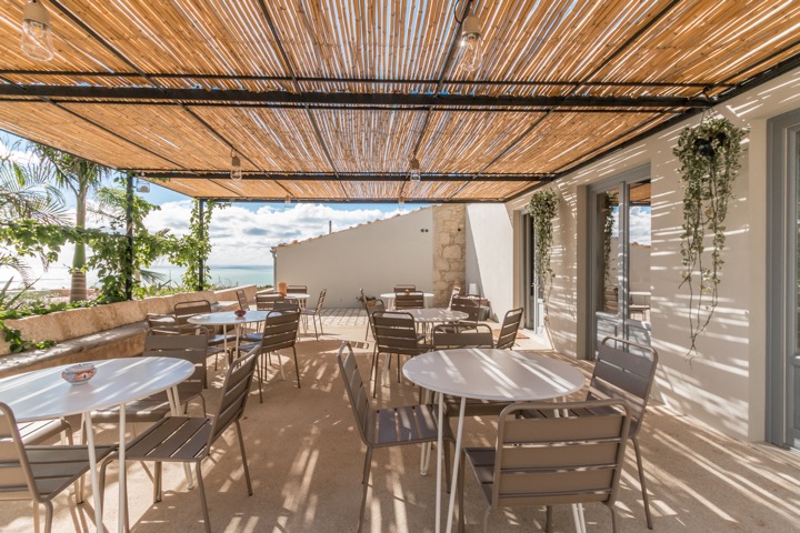 Espace extérieur ombragé pour le petit-déjeuner à Mangiabove, avec tables et vue dégagée sur la campagne de Raguse.