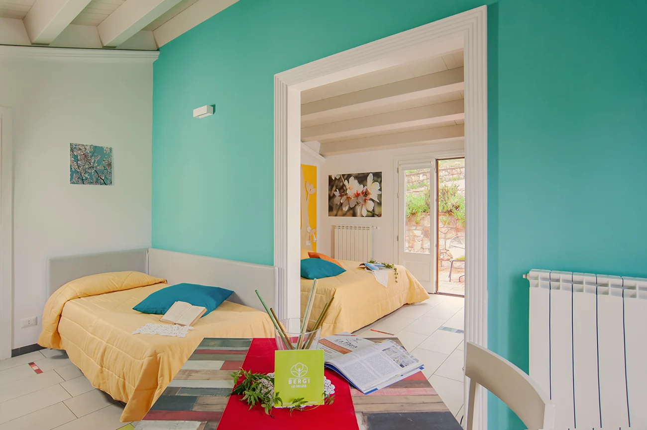 Ferme Bergi – Suite familiale Deluxe avec lits doubles, mobilier moderne aux tons bleus et jaunes, lumineuse et accueillante, à Castelbuono, Sicile.